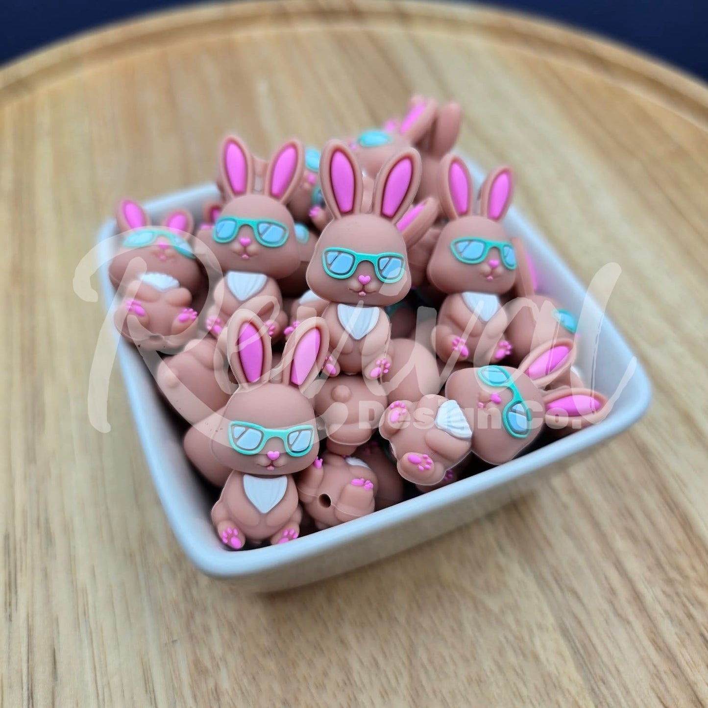 Small rabbit-shaped beads with sunglasses on a wooden surface