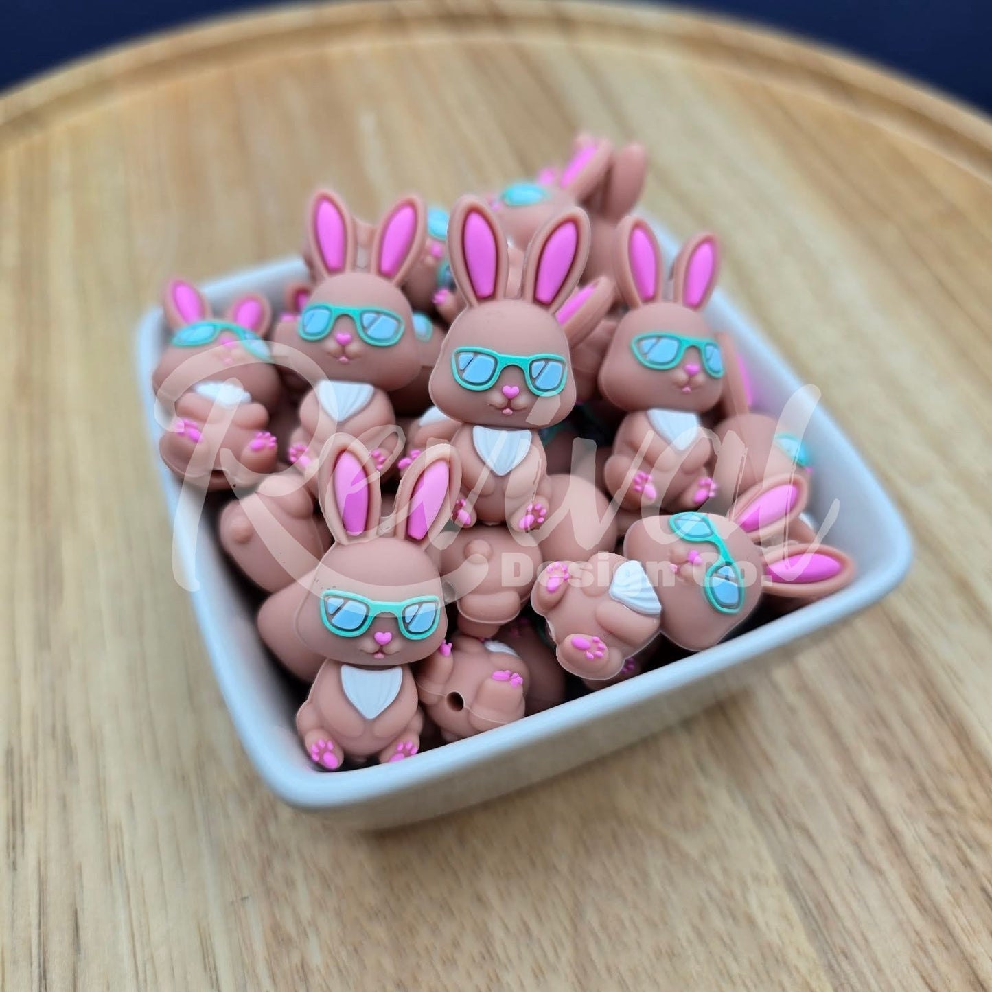 Small rabbit-shaped beads with sunglasses on a wooden surface