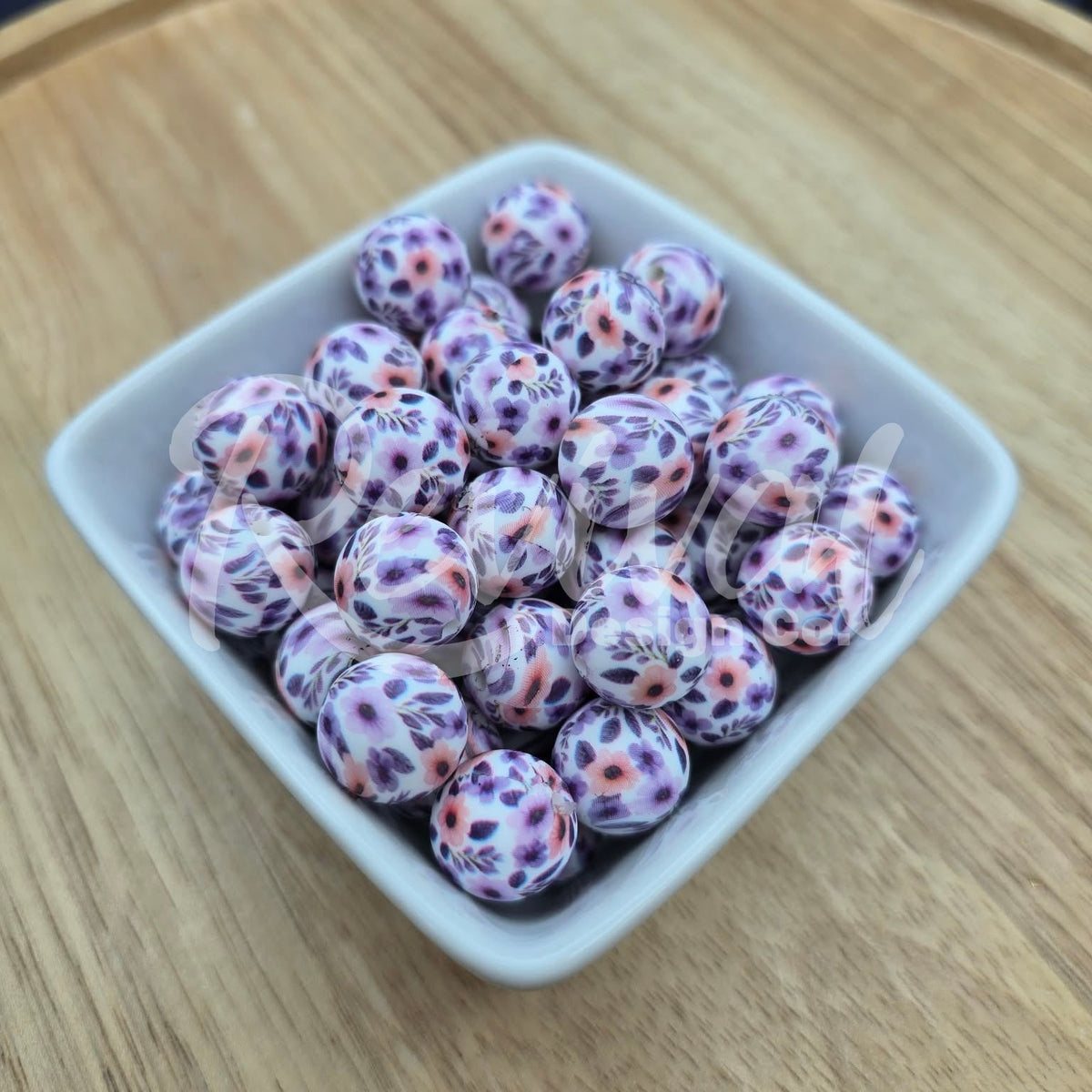 White container filled with purple and pink floral beads on a wooden surface