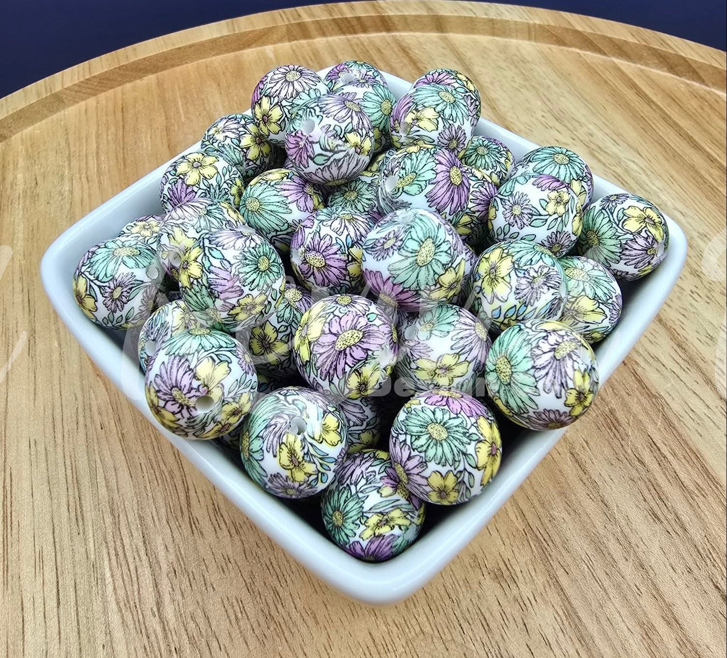 Decorative balls with floral patterns in a white bowl on a wooden surface