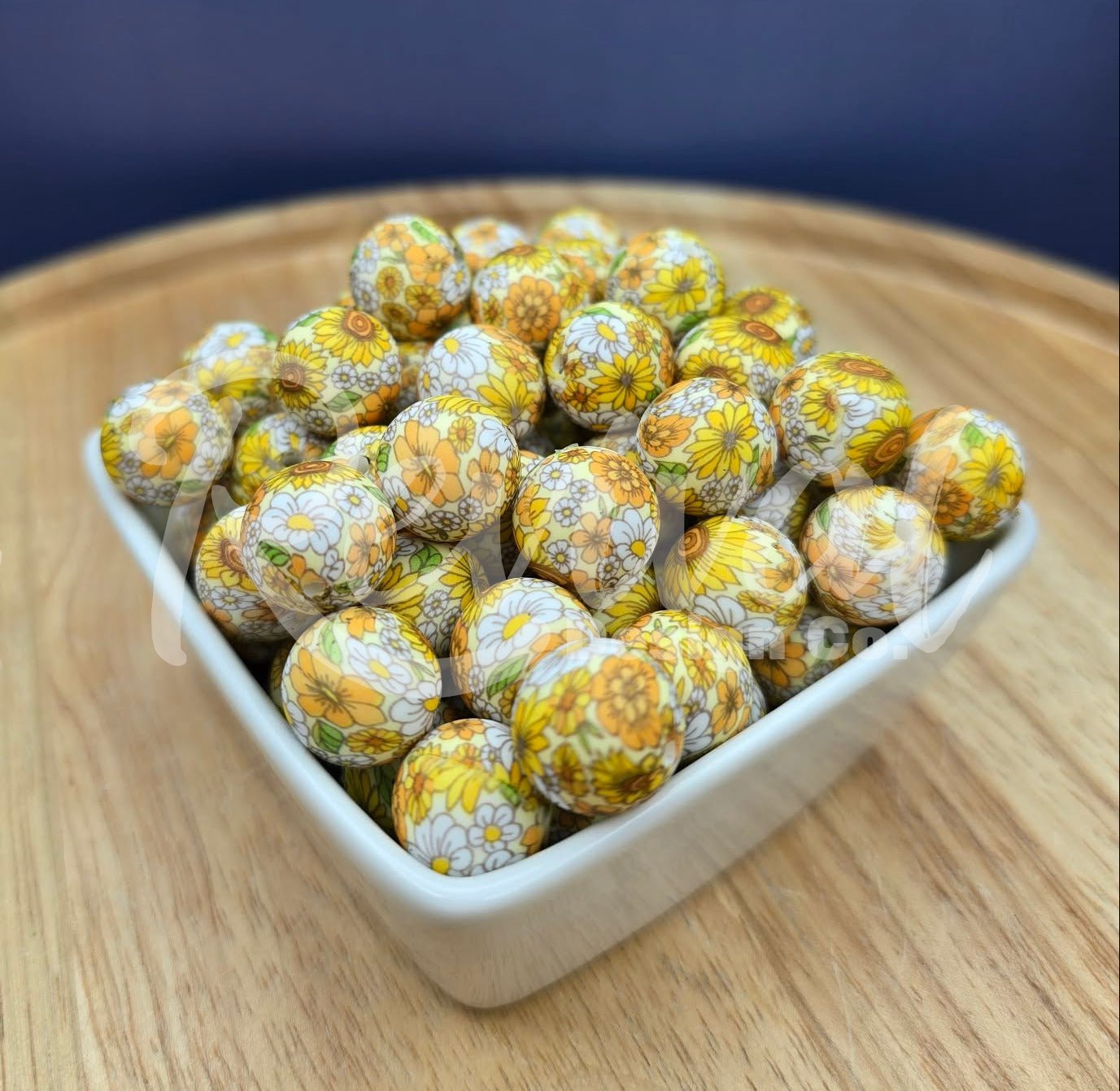 White container filled with yellow and white spherical beads on a wooden surface with a dark blue background