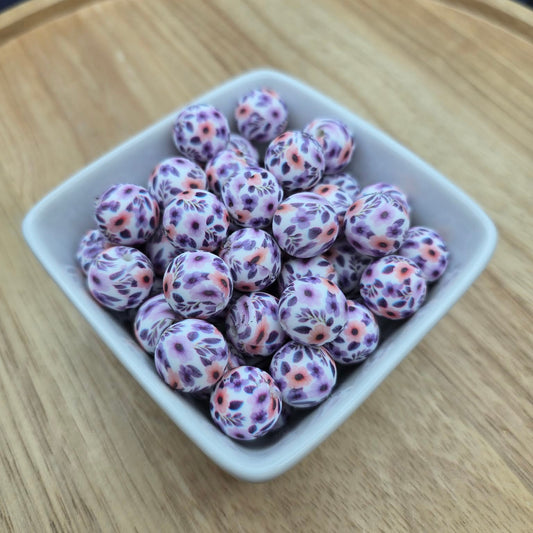 White container filled with purple and pink floral beads on a wooden surface